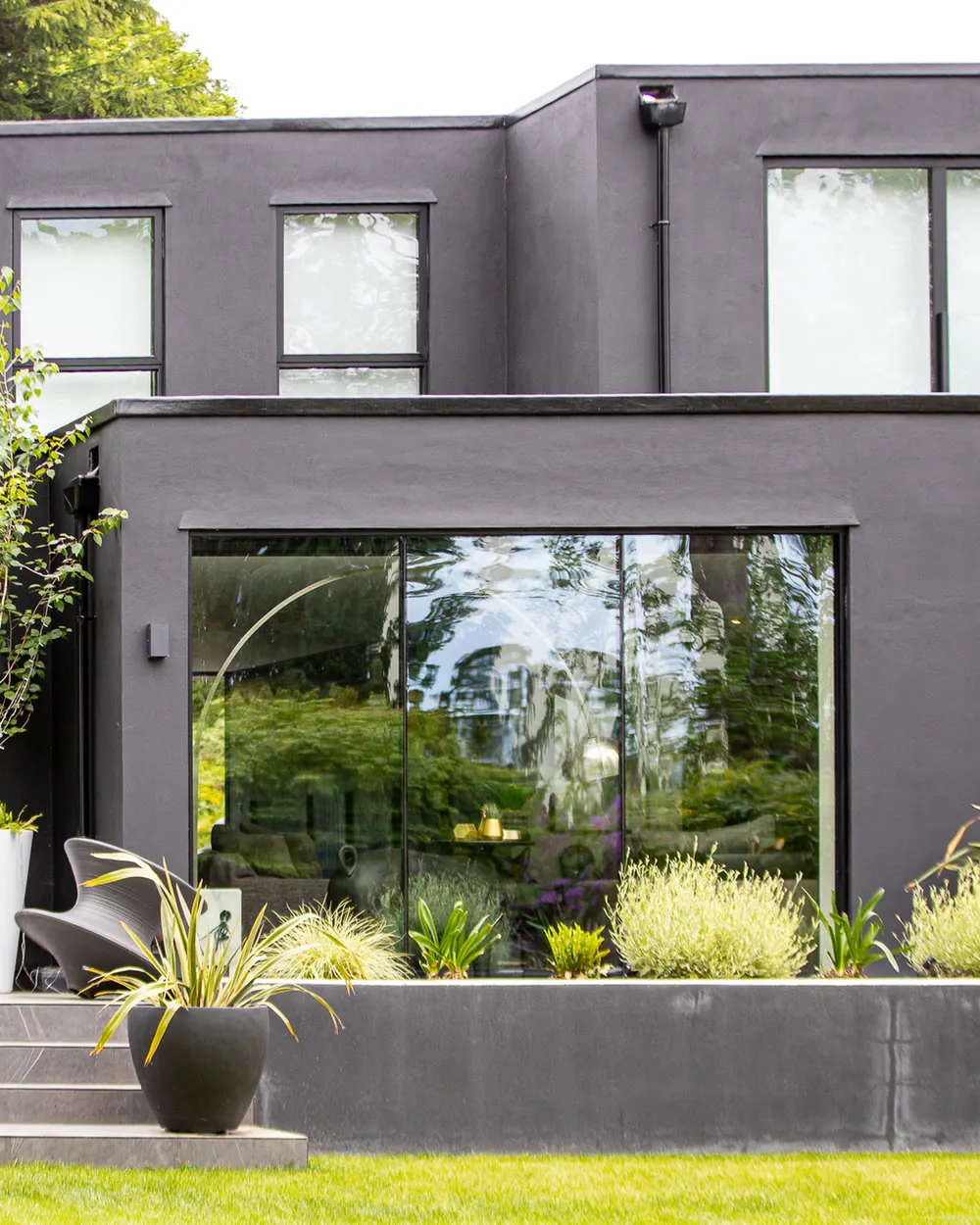 Charcoal House, Bromley: dark rendered rear extension with full-width glazing